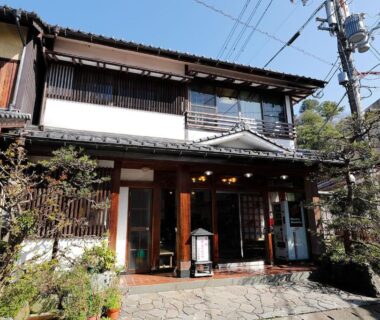 Traditional wooden facade and entrance of Yanagi-sō ryokan in Hyōgo Kansai with potted plants and street setting