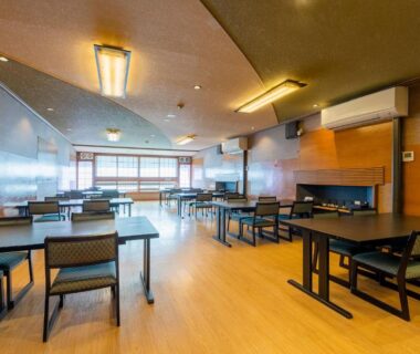 Spacious dining area with wooden floors, tables and chairs, large windows and warm lighting at Yanagi-sō, Hyōgo