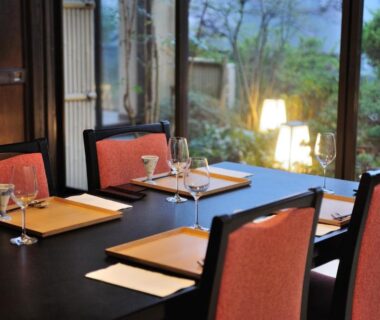 Dining table with wine glasses and placemats beside garden-facing window at Auberge Hanagoyomi, Shizuoka, Chūbu, Japan