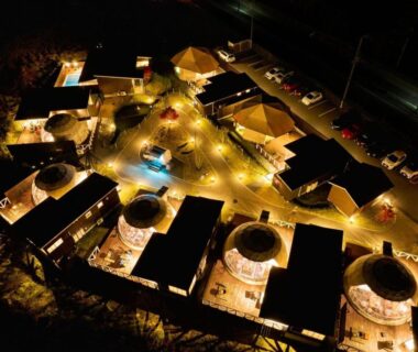 Aerial night view of illuminated ryokan villas with round outdoor baths, Grandome Fuji Oshino, Yamanashi