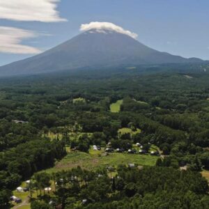 Aerial view of Mount Fuji above forested Kawaguchiko landscape with glamping tents and grassy sites