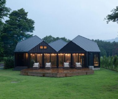 Three wooden cabins with lit decks on a grassy lawn at Glamping Village Fuji Kawaguchiko, Yamanashi