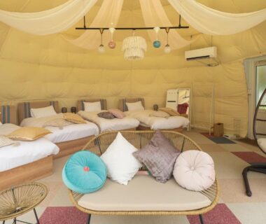 Glamping tent interior with multiple beds, draped ceiling and lounge seating at Glamping Village Fuji Kawaguchiko in Yamanashi