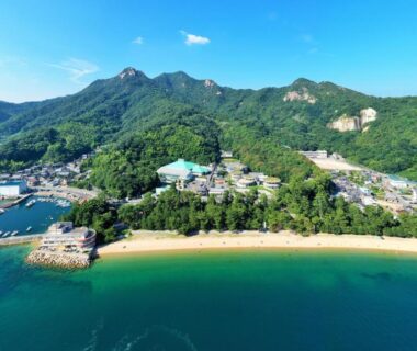 Aerial view of beachside Seaside Katsuragahama-sō, sandy shore and forested hills in Hiroshima, Chūgoku