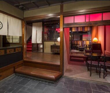 Entrance and lounge area with wooden step, noren curtain and cozy seating at Dozen-Ryokan＆Cafe in Kyoto