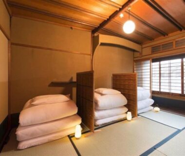 Traditional tatami room with folded futons, shoji screens and wooden ceiling at Dozen Ryokan Kyoto