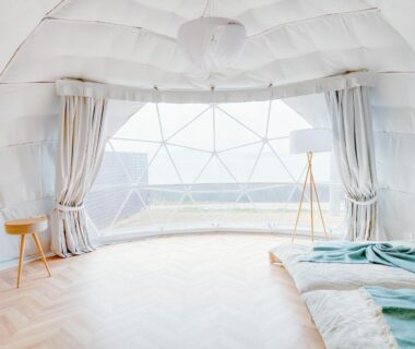Geodesic dome interior with low bed, wooden stool and wide curved window at Hitotsuru in Setouchi, Hiroshima
