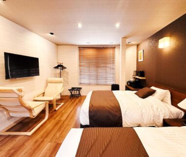 Western-style twin room with two beds, lounge chairs, TV and wooden floor in Hitotsuru Setouchi Hiroshima