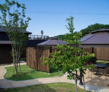Grassy courtyard with wooden cabins and outdoor seating at Hitotsuru in Setouchi, Hiroshima
