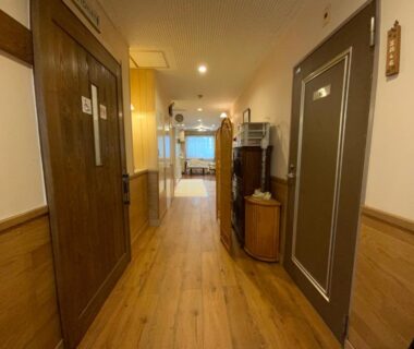 Wooden corridor with guest room doors and reception area at Business Inn Haijima in Tokyo