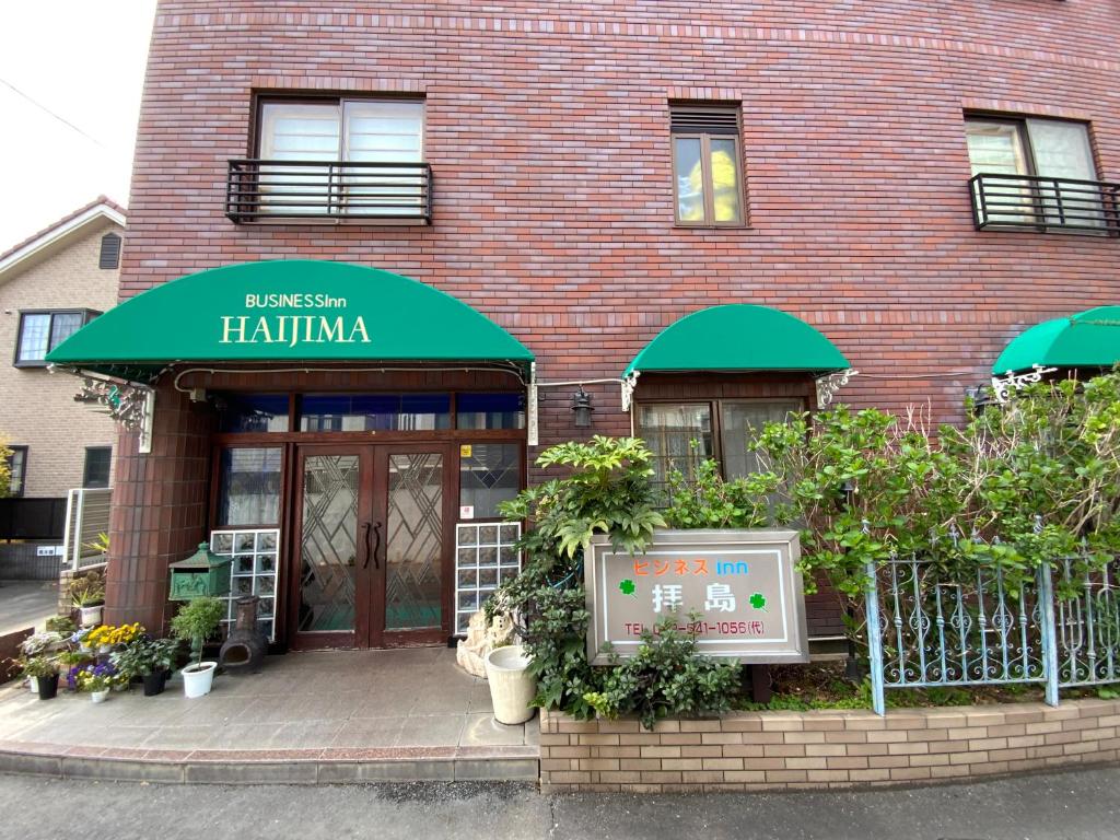 Brick entrance of Business Inn Haijima Tokyo Street-level brick facade with green awnings and potted plants at Business Inn Haijima entrance in Tokyo, Kantō