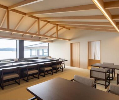 Spacious tatami dining area with tables and large windows overlooking water at 一 能登島, Ishikawa, Chūbu
