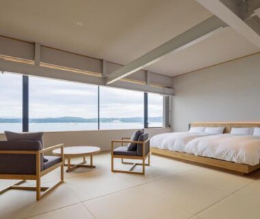 Spacious tatami room with low beds, seating and sea view at Hitotsu Notojima, Ishikawa