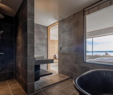 Freestanding tub and shower beside large window with sea view in a tiled bathroom at 一 能登島, Ishikawa