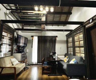 Traditional room with exposed wooden beams, sofas, low table and shoji screens at Ichishuku Ikkei Isshōen, Chiba