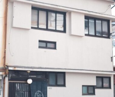 Three-story white facade with noren curtain and multiple windows at Kabukiya in Hiroshima