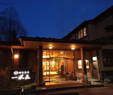 Lit ryokan entrance with glass doors and signboard at dusk, Ichisui-sō, Niigata, Chūbu, Japan