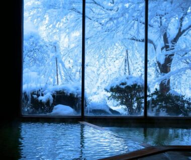 Indoor onsen bath with large windows overlooking snow-covered garden at Ichisui-sō in Niigata, Chūbu region