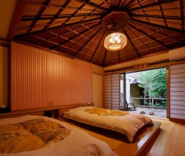 Traditional tatami room with futon bedding and shoji doors opening to a courtyard garden at Sanpei-sō in Shizuoka
