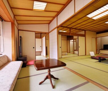 Spacious tatami room with low table, sofa bench, shoji screens and sliding doors at Sanpei-sō Shizuoka