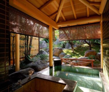 Covered wooden onsen with bamboo blinds overlooking a moss garden at Sanpei-sō in Shizuoka, Chūbu