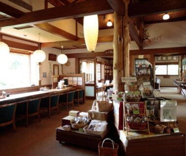 Wooden ryokan lobby with merchandise display, counter seating and large windows at Nakadana-sō in Nagano, Chūbu