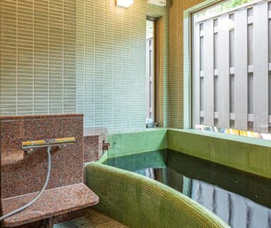 Green tiled soaking tub and shower in bathing room at 五氣里-itsukiri- Chiba