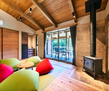 Vaulted wooden lounge with wood stove and colorful floor cushions at 五氣里-itsukiri- in Chiba, Kantō