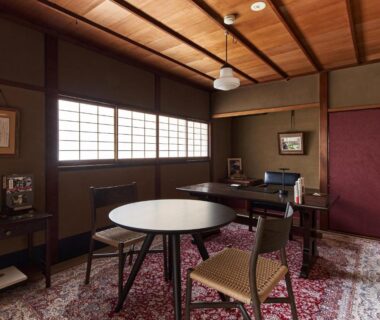 Traditional sitting room with round table, woven chairs, wooden ceiling and shoji screens at Kyo no Yado Ishihara Kyoto