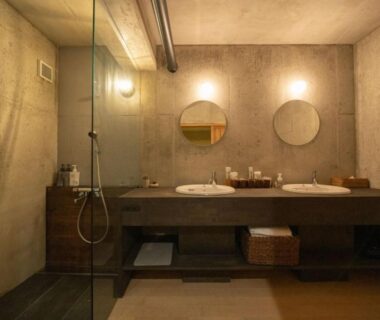 Concrete-walled bathroom with double sinks and round mirrors at 京都松澗Matsutani in Kyoto, Kansai