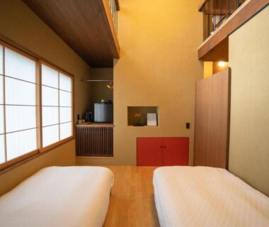 Two low beds on wooden floor with shoji screens and warm wood interior at Kyoto ryokan