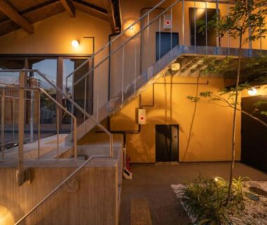 Warm-lit courtyard with staircase, wooden beams and small rock garden at Kyoto Matsutani
