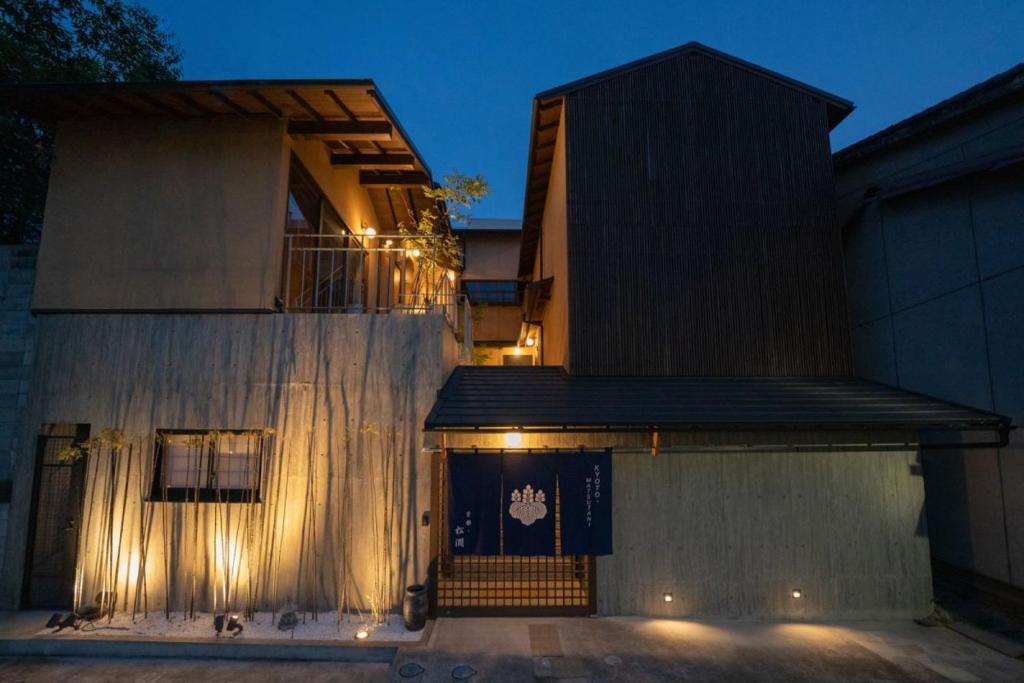 Wooden ryokan facade at Kyoto Matsutani Nighttime exterior of Matsutani with illuminated wooden facade and noren at Kyoto entrance