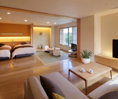 Bright room with tatami area, twin beds and seating by window at Ryokusuitei in Miyagi