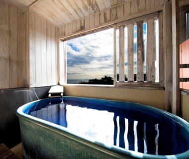 Blue ceramic bath in wooden room with window showing distant trees and sky at 伊豆高原の隠れ宿Syuhari守破離 Shizuoka