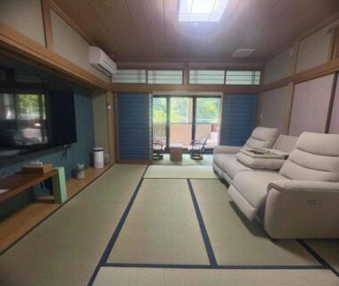 Japanese tatami room with reclining sofas, low table, TV and sliding doors to veranda at Shinobu Onsen Seishū Fukushima