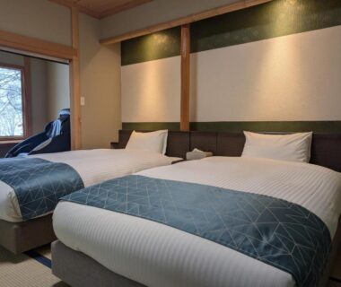 Twin beds on tatami with shoji window and reclining chair at Shinobu Onsen Seishū, Fukushima