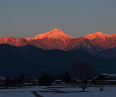 Snowy fields and alpenglow on mountain peaks at sunset near Ryokan Yama no Takohei, Hotaka Onsen, Nagano