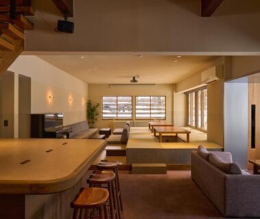 Open-plan interior with tatami platform, low tables, wooden counter stools and shoji windows at Iriyamato in Nagano