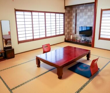 Traditional tatami room with low table, floor chairs and shoji screens at Manrikiya in Beppu, Oita