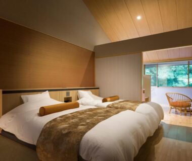 Tatami room with twin beds, low wooden ceiling and garden-view seating area at Hakkaisan Konohanakan