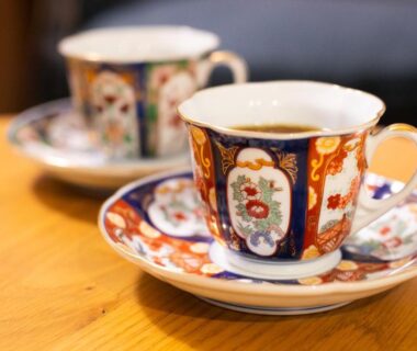 Pair of decorative porcelain teacups on saucers on a wooden table at Manrikiya Bekkan Beppu