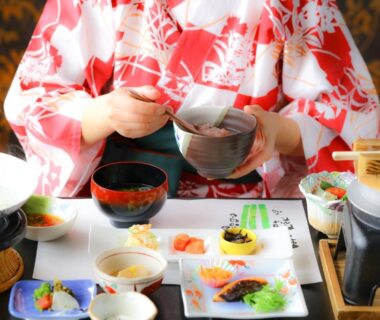 Guest in kimono pouring tea beside assorted small dishes at Nanakusa no Yu, Bessho Onsen, Nagano