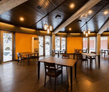 Wooden tables and chairs in warm dining area at Bettei Tateshina Kunpū, Nagano, Japan