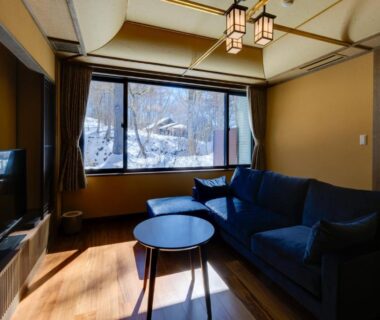 Sofa and low table facing large window with snowy mountain view in Bettei Tateshina Kunpū room, Nagano