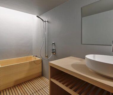 Minimal ryokan bathroom with wooden ofuro tub, wall-mounted shower, vessel sink and slatted wooden floor