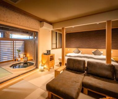 Warm tatami room with bed, seating area and sunken wooden bathing tub by shoji window