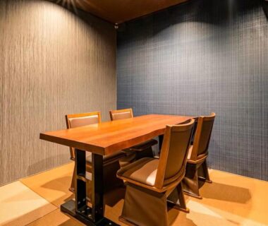 Wooden dining table with four chairs on tatami flooring, textured walls at Kappō Ryokan Kiyoto Chiba