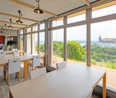 Spacious dining area with floor-to-ceiling windows overlooking coastline near Kachōfūgetsu in Nanki Shirahama