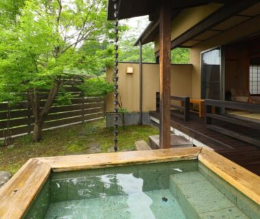 Wooden outdoor bath beside tatami veranda, shoji screens and a small green garden